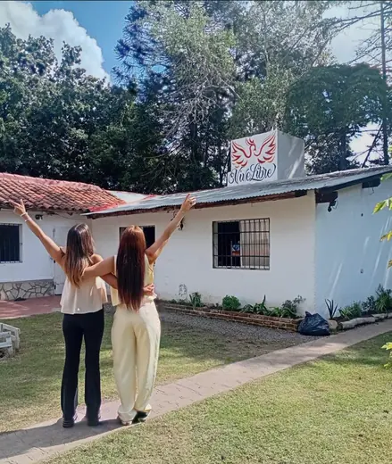 Dos compañeras celebrando frente a la casa de la comunidad
